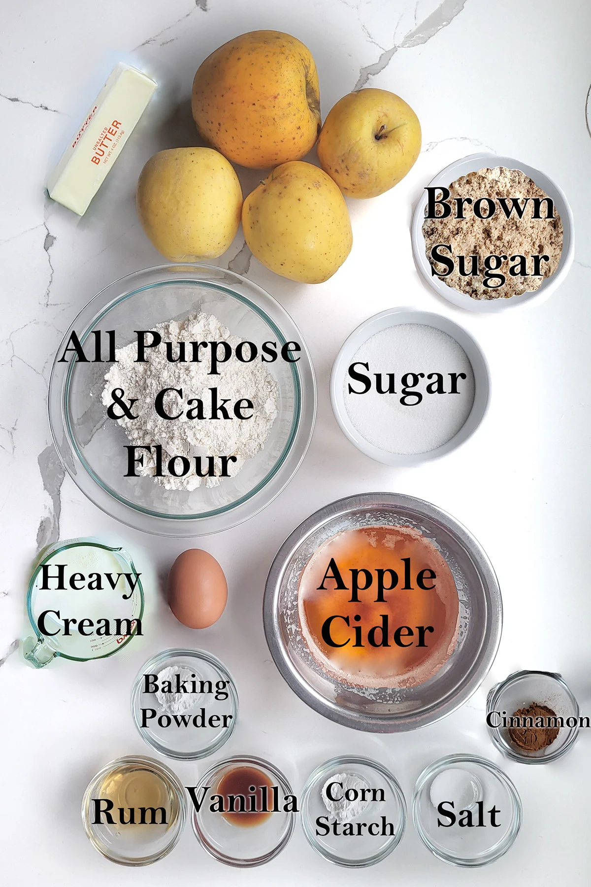 ingredients for apple cobbler in glass bowls on a white surface.