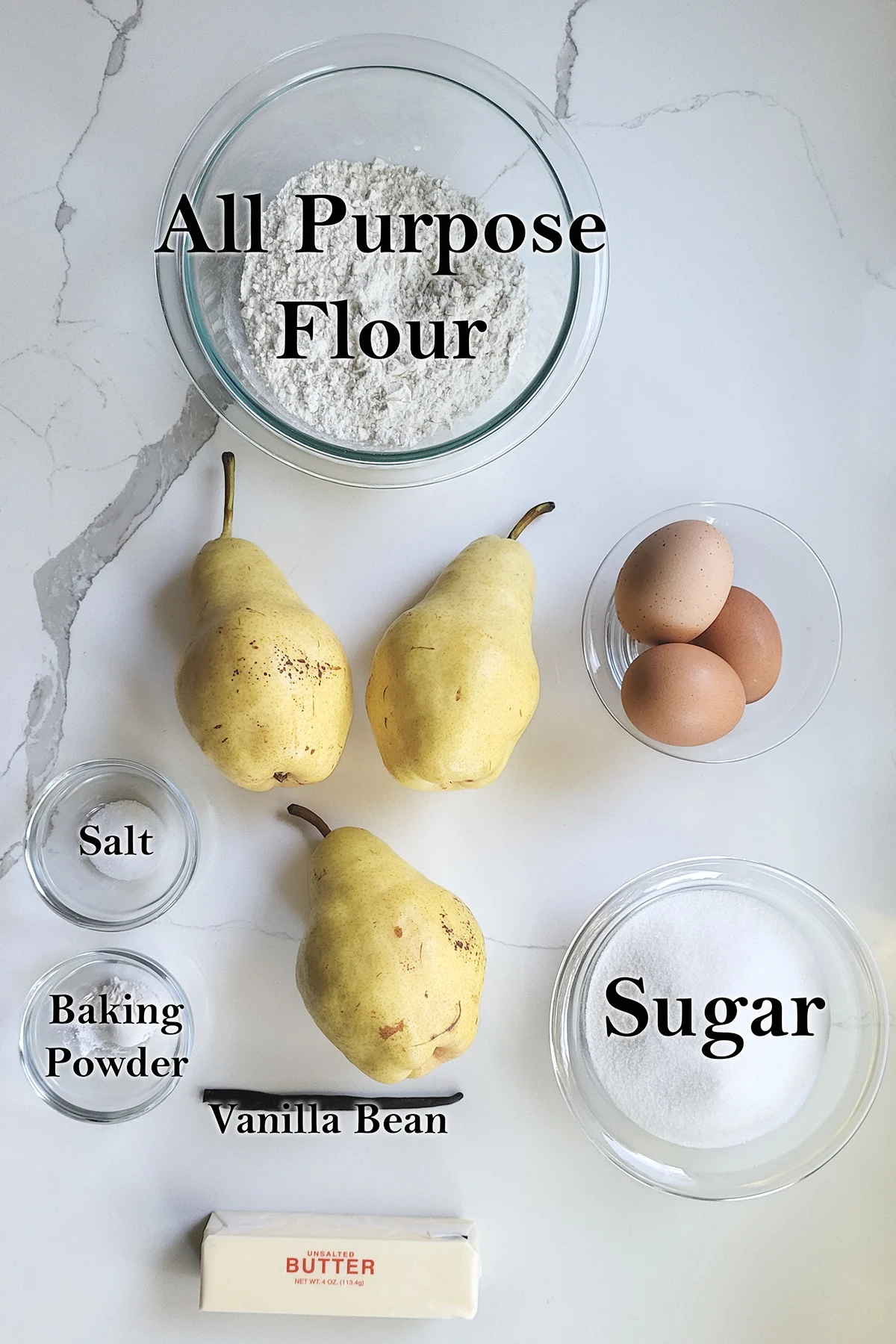 ingredients for pear cake in glass bowls on a white surface.