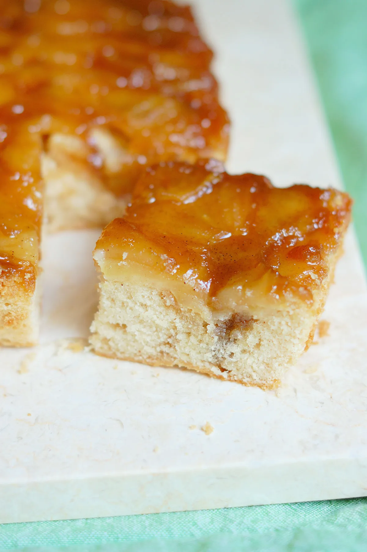 a slice of apple upside down cake on a marble board.