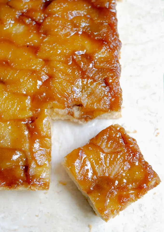 a slice apple upside down cake on a marble board.