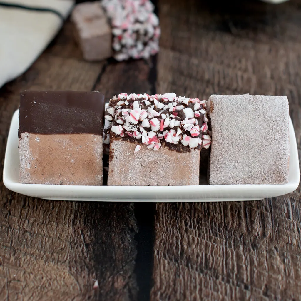 three chocolate marshmallows on a plate.