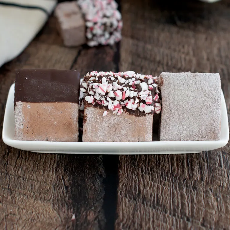 three chocolate marshmallows on a plate.