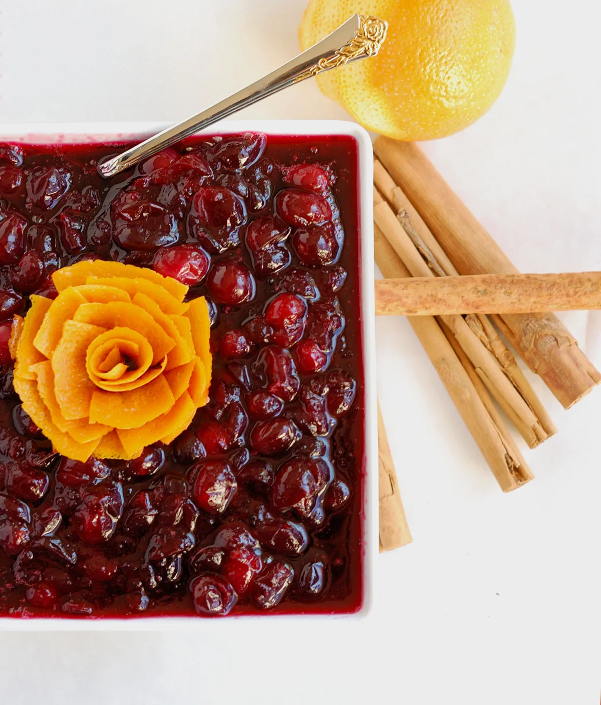 a bowl of cranberry compote with an orange peel rose on top.