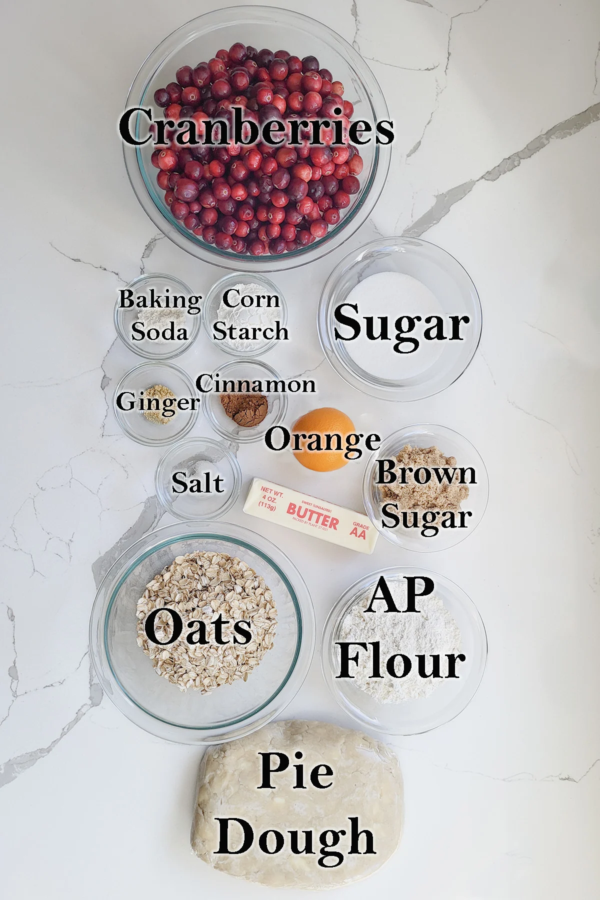 ingredients for cranberry crumb pie in glass bowls on a white surface.
