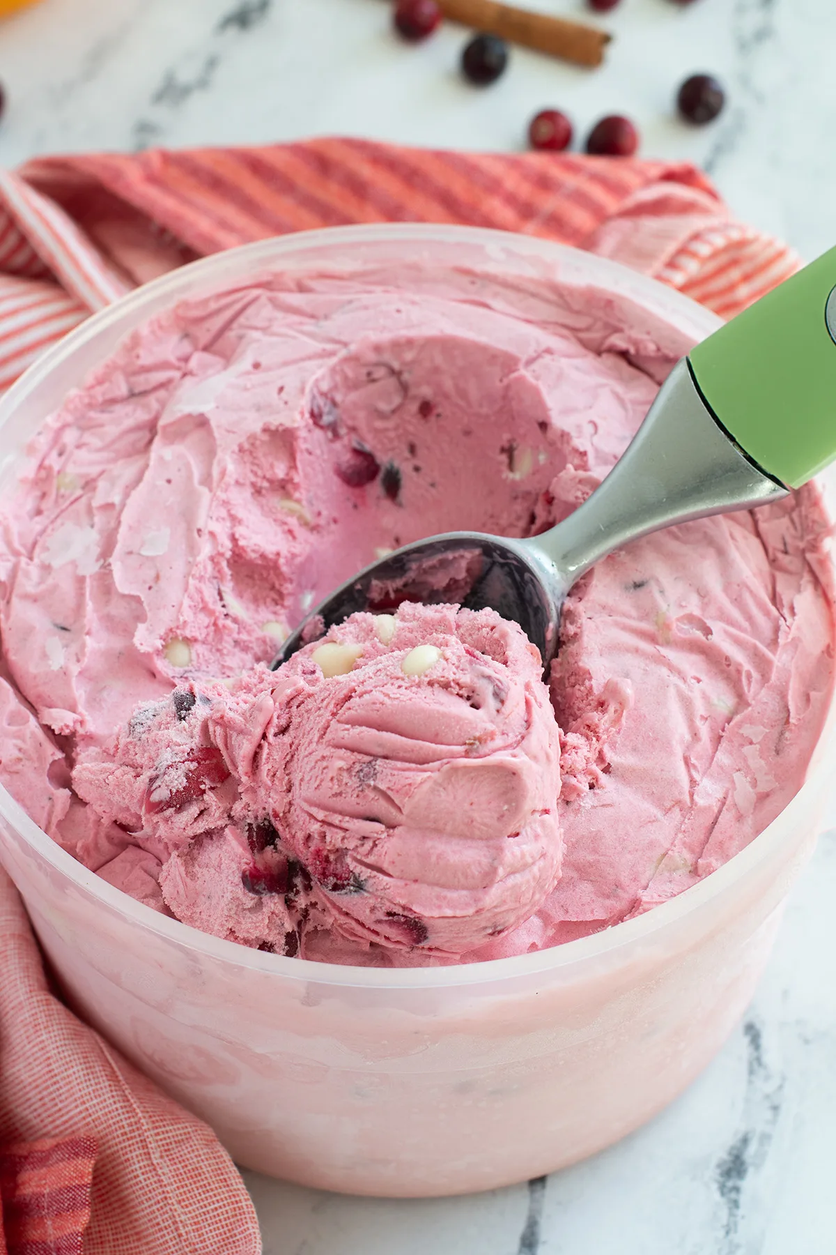 a bucket of cranberry ice cream with a green scooper.
