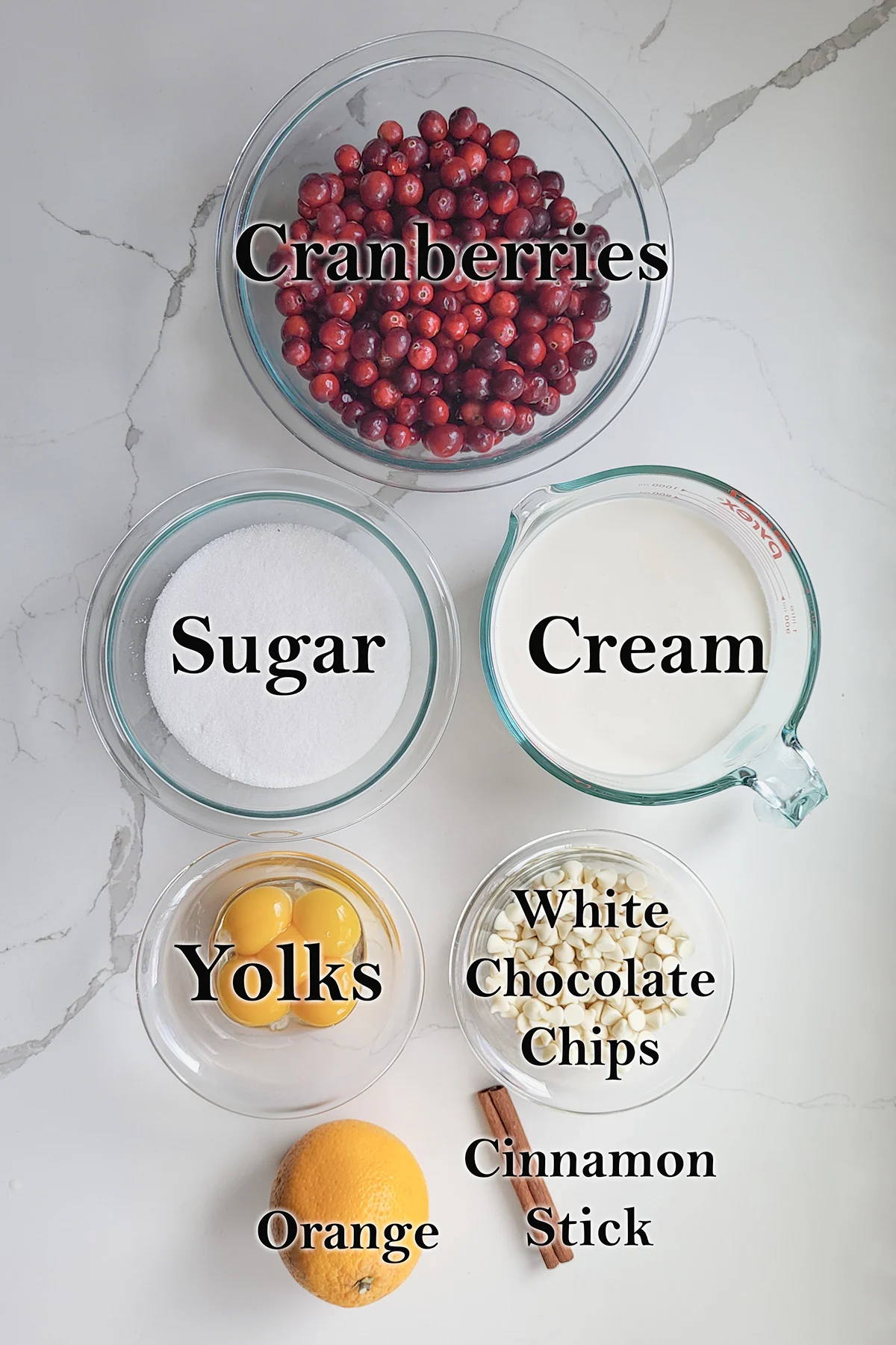 ingredients for cranberry ice cream in glass bowls on a white surface.