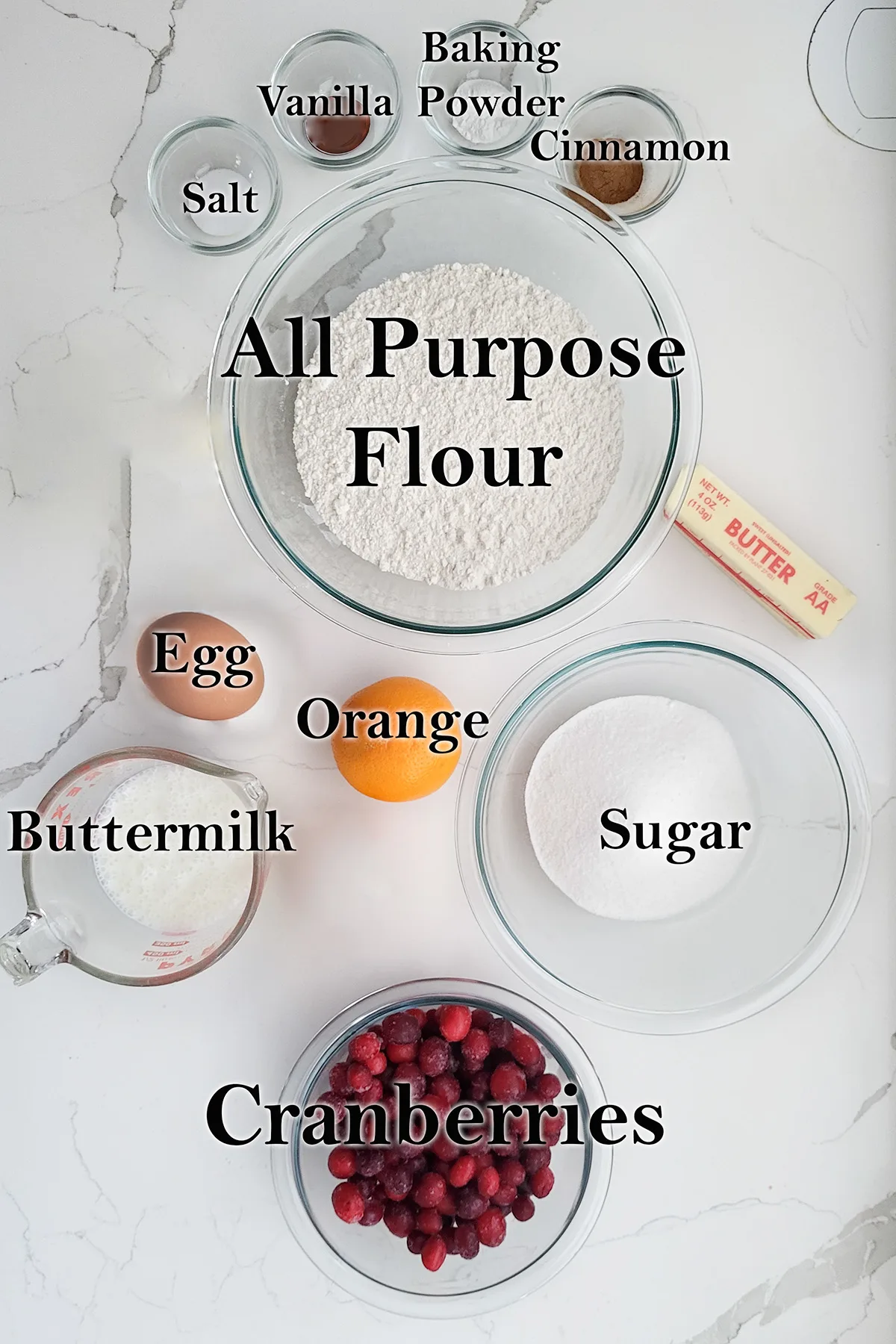 ingredients for cranberry scones in glass bowls on a white surface.