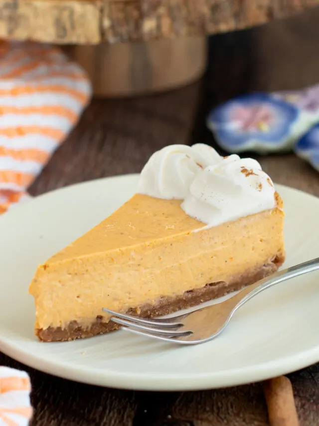 a slice of pumpkin cheesecake on a white plate with a fork.
