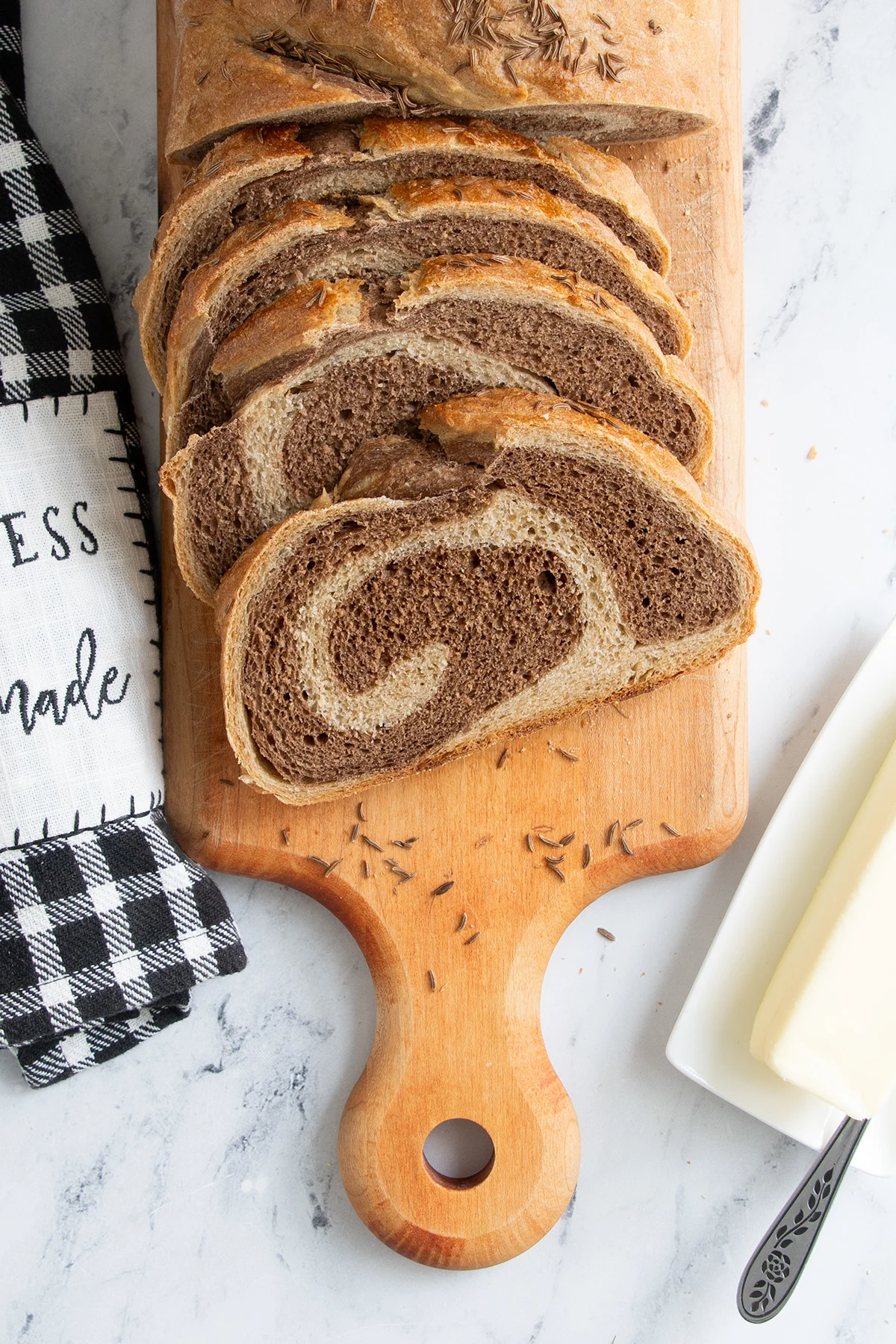 a sliced loaf of marble rye bread on a cutting board.
