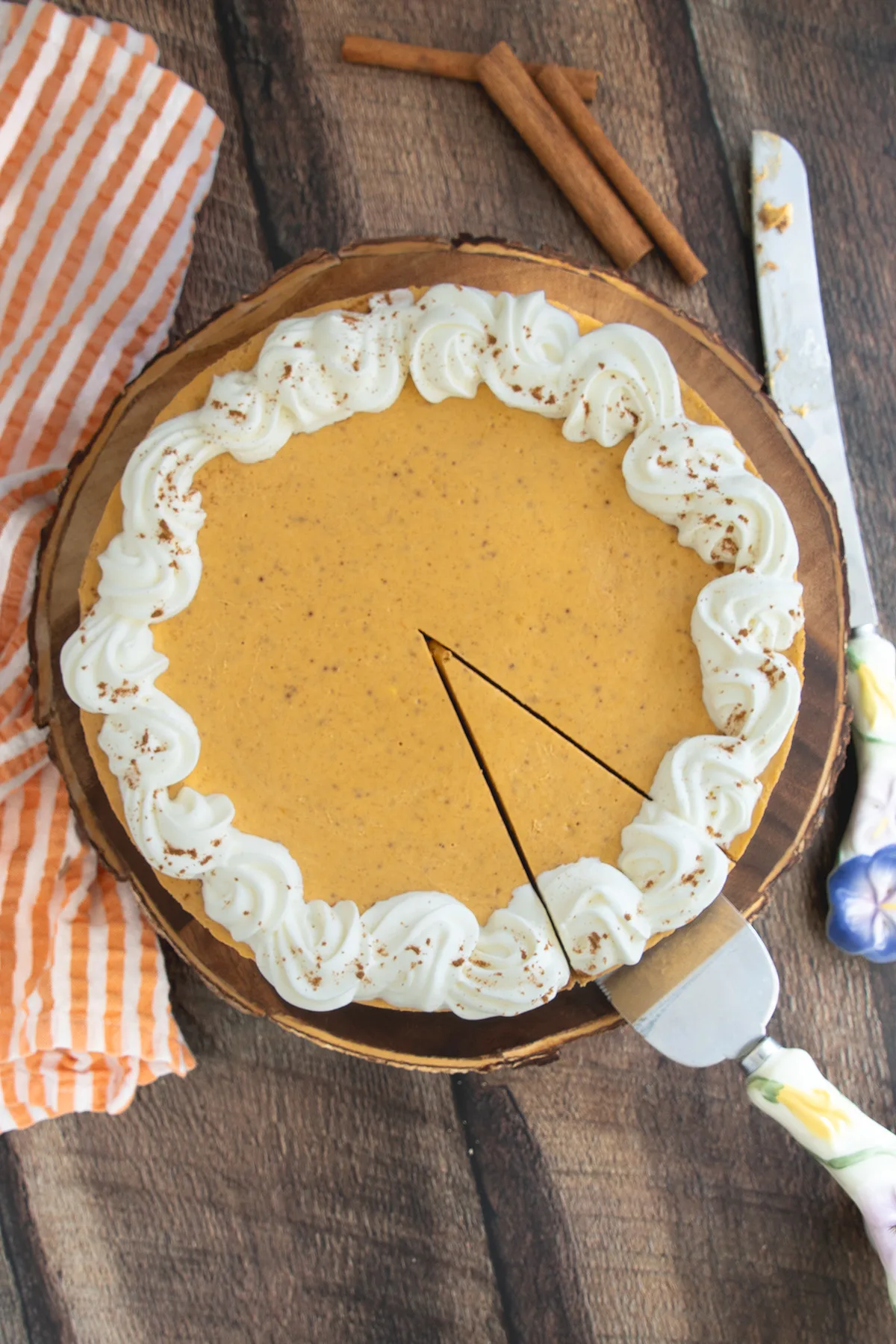 a pumpkin cheesecake on a wood cake stand.