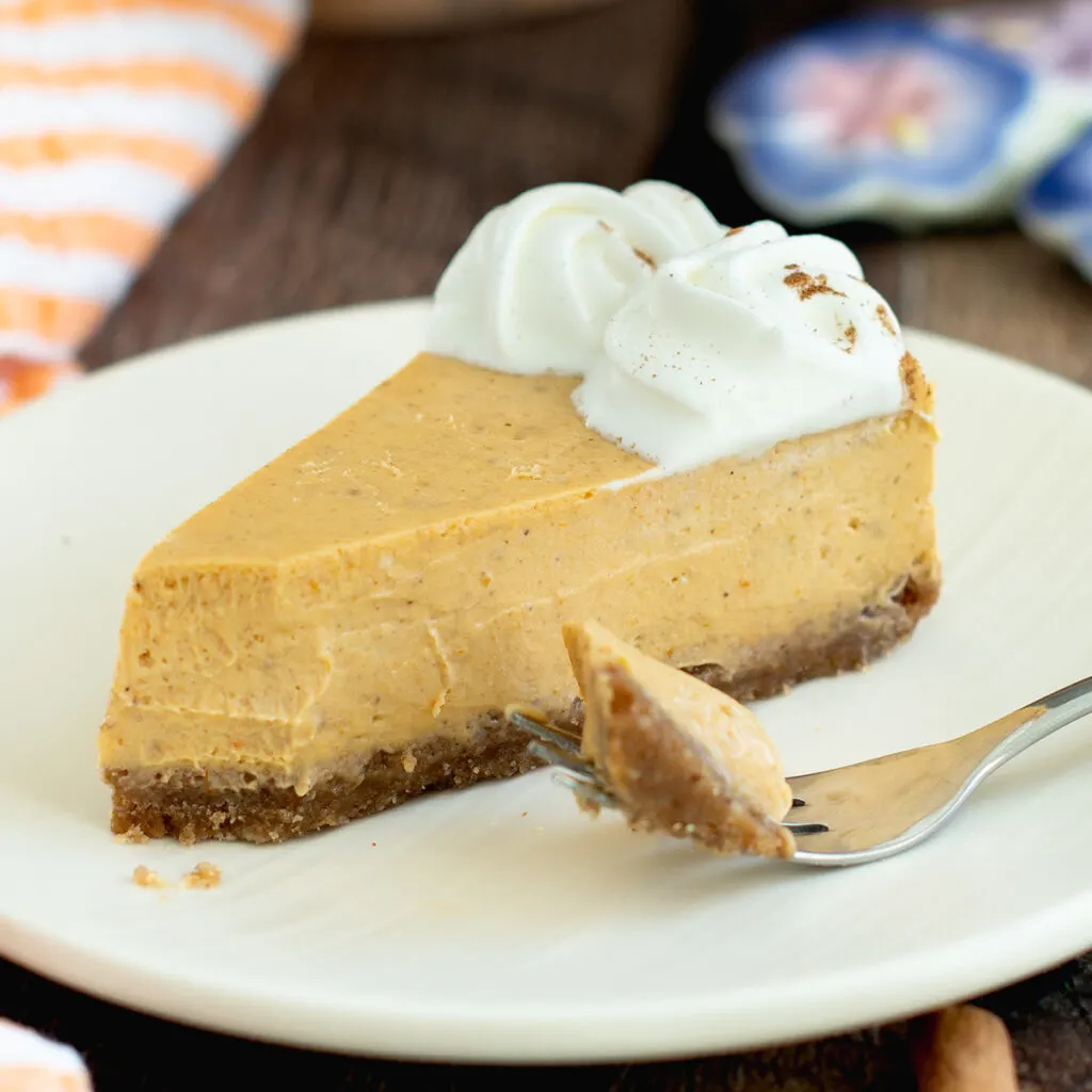 a slice of pumpkin cheesecake on a white plate with a fork.