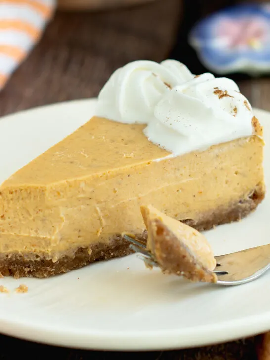 a slice of pumpkin cheesecake on a white plate with a fork.