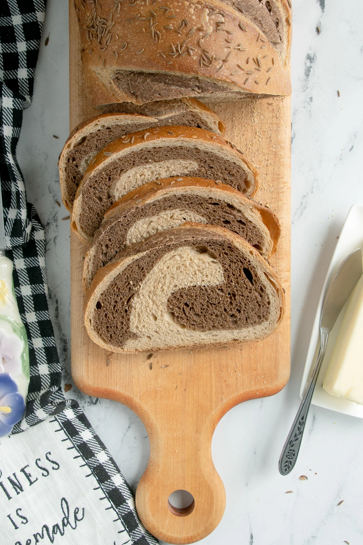 a sliced loaf of sourdough marble rye bread on a cutting board.