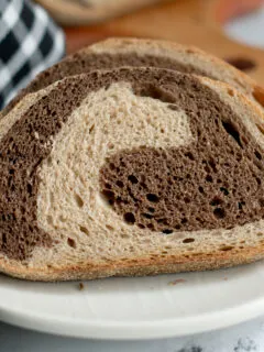 a slice of sourdough marble rye bread on a white plate.