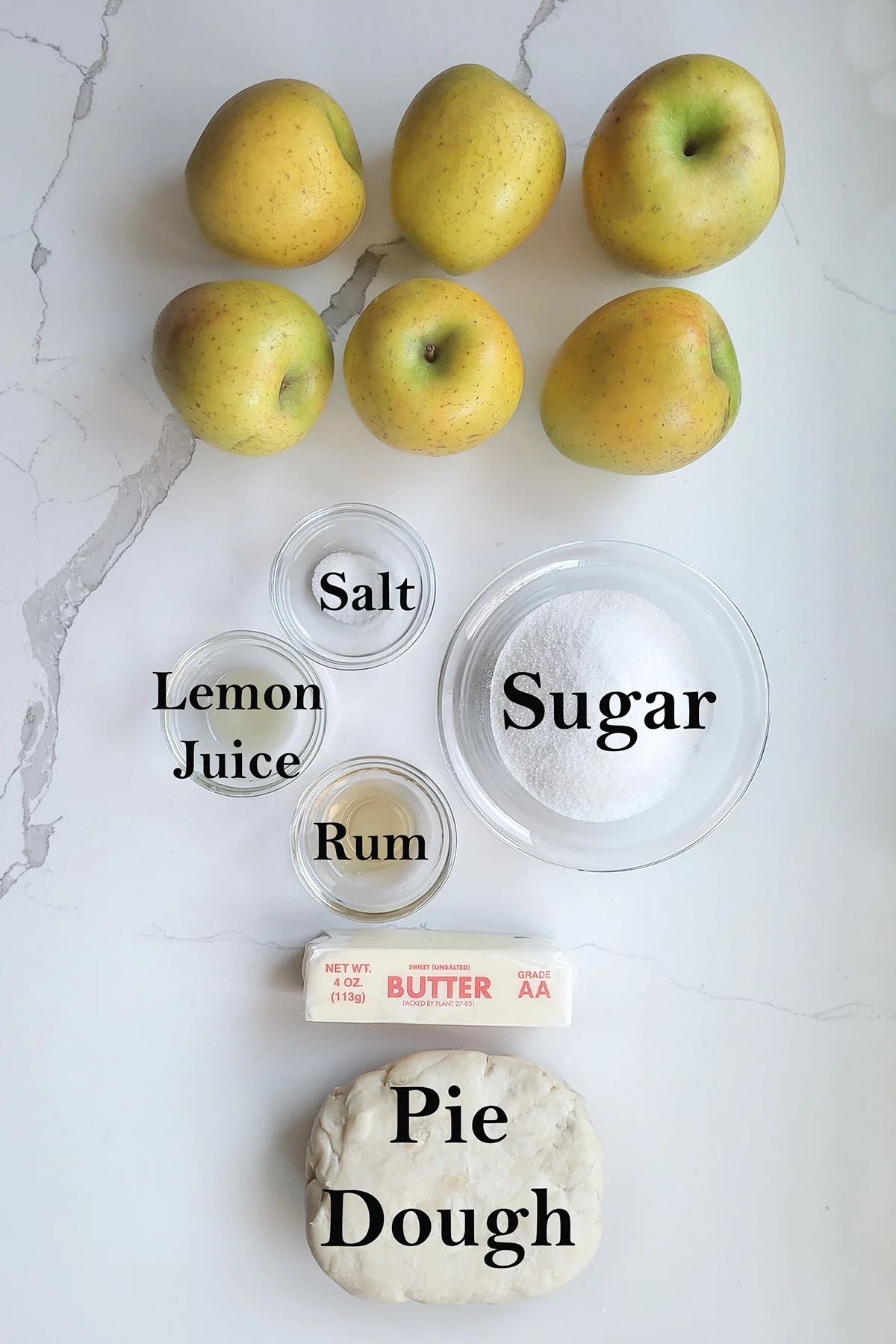 ingredients for apple tarte tatin in glass bowls on a white surface.