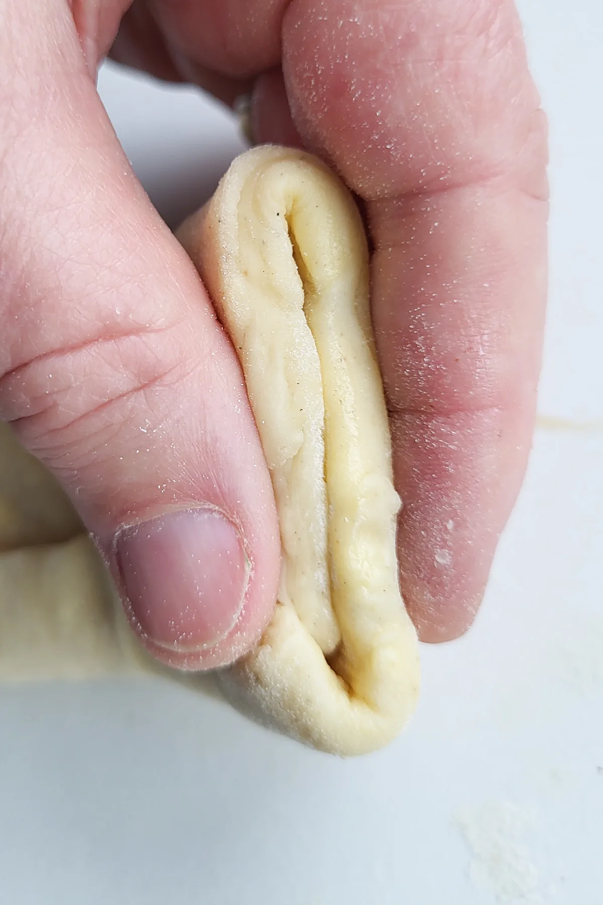 a hand pinching dough together.