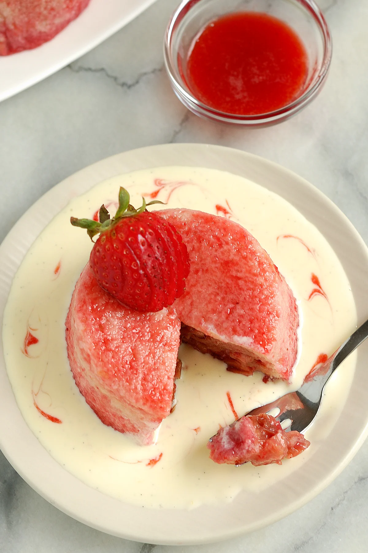 a rhubarb summer pudding on a plate of creme anglaise.