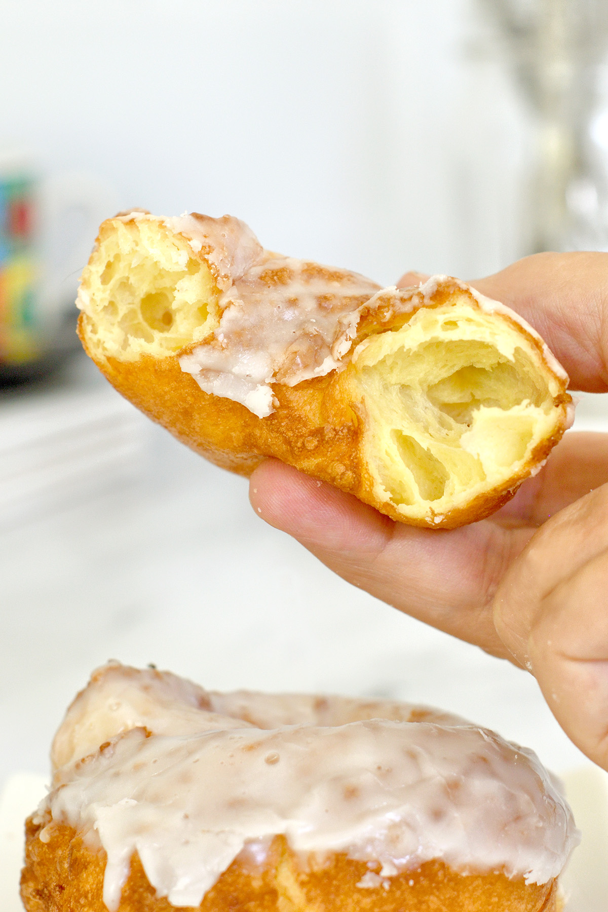 a hand holding half a cruller donut.