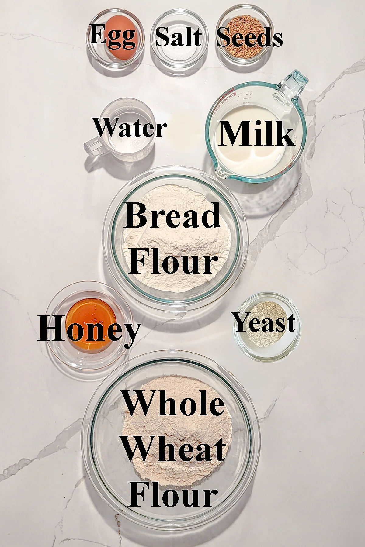 Ingredients for whole wheat bread in glass bowls.