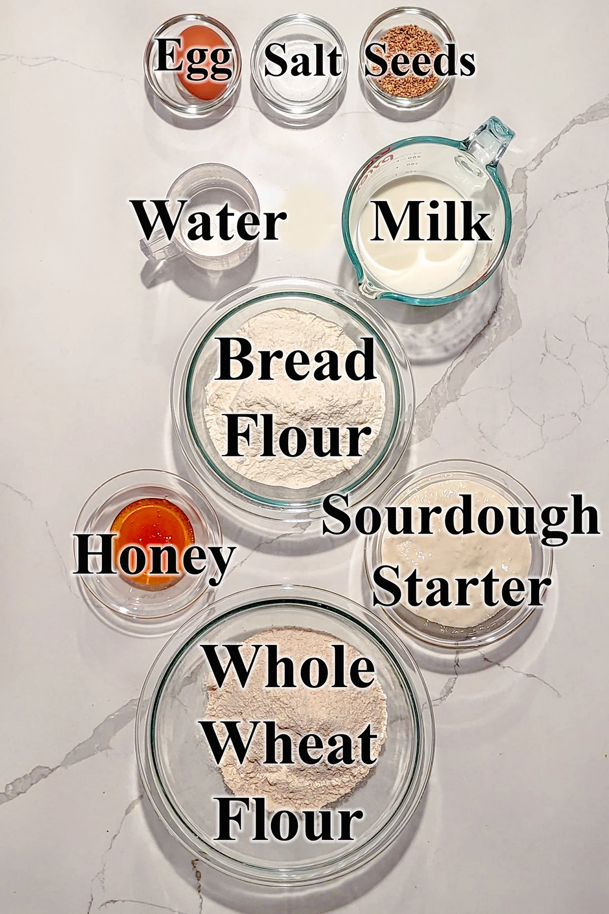 ingredients for sourdough whole wheat sandwich bread in glass bowls.