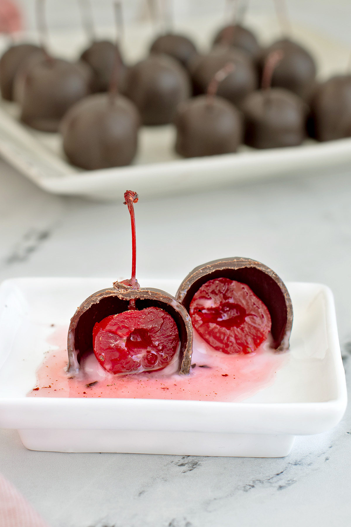 an open cherry cordial candy on a white plate.