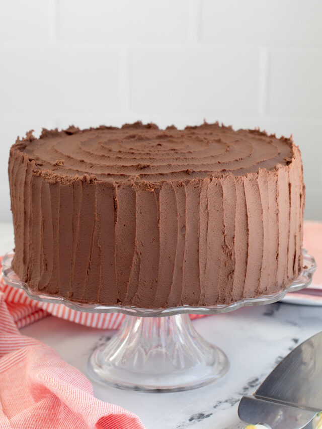 a chocolate cake on a glass cake stand.