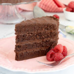 a slice of chocolate ganache cake on a pink plate.