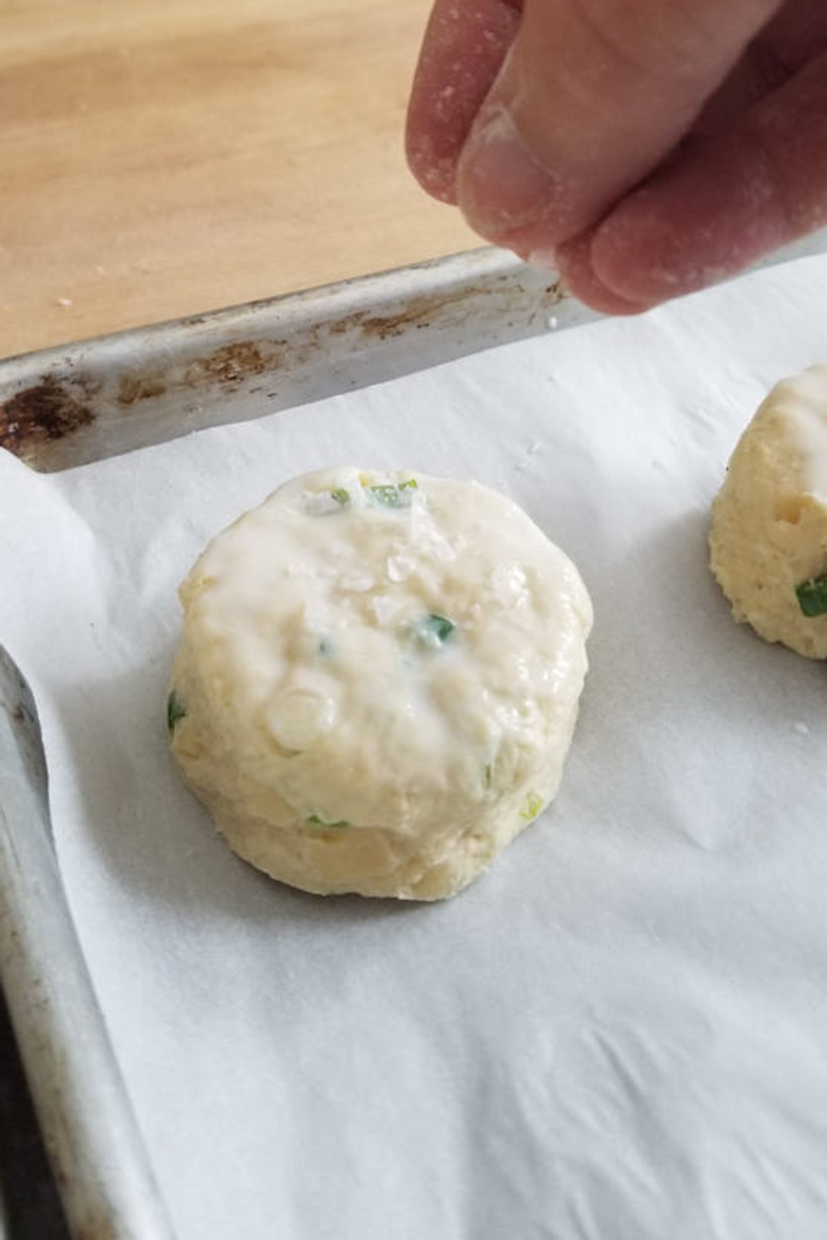 a hand sprinkling salt onto a scone.
