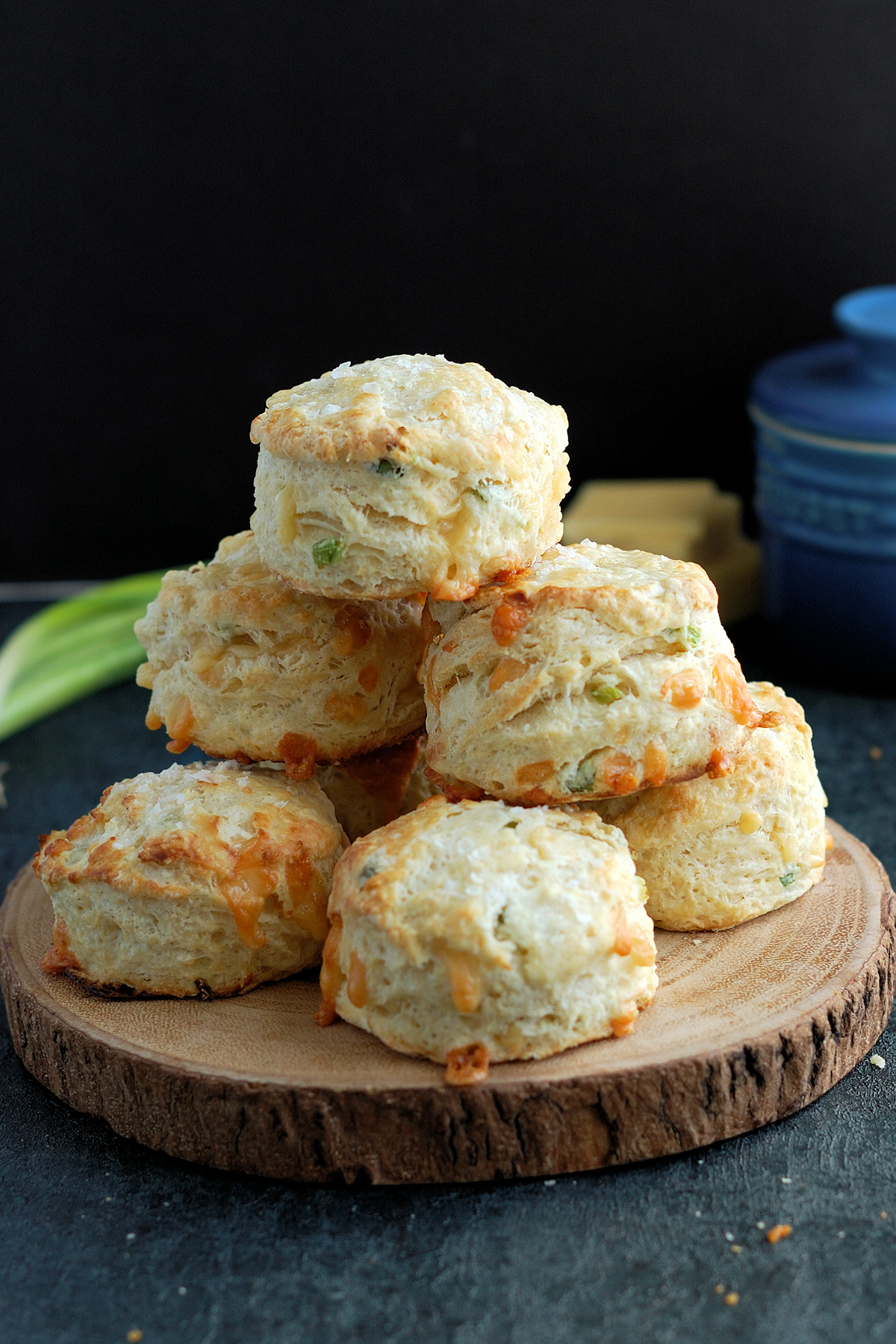 a wood plate with a stack of cheese scones.