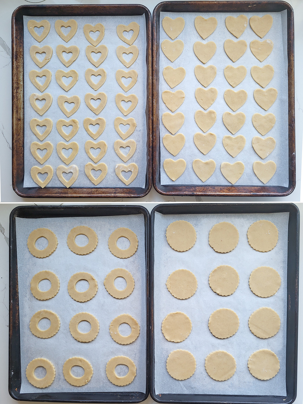 Four cookies sheets with heart and round cookie cut outs.