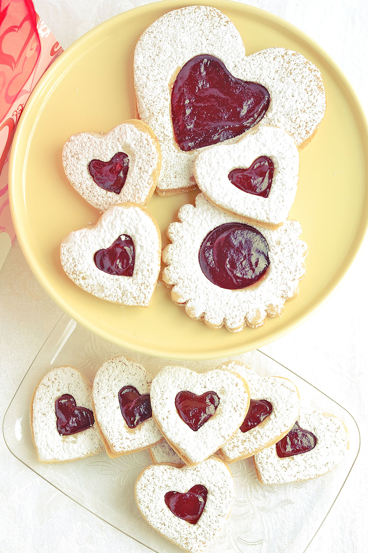 Raspberry Linzer cookies on a yellow plate.