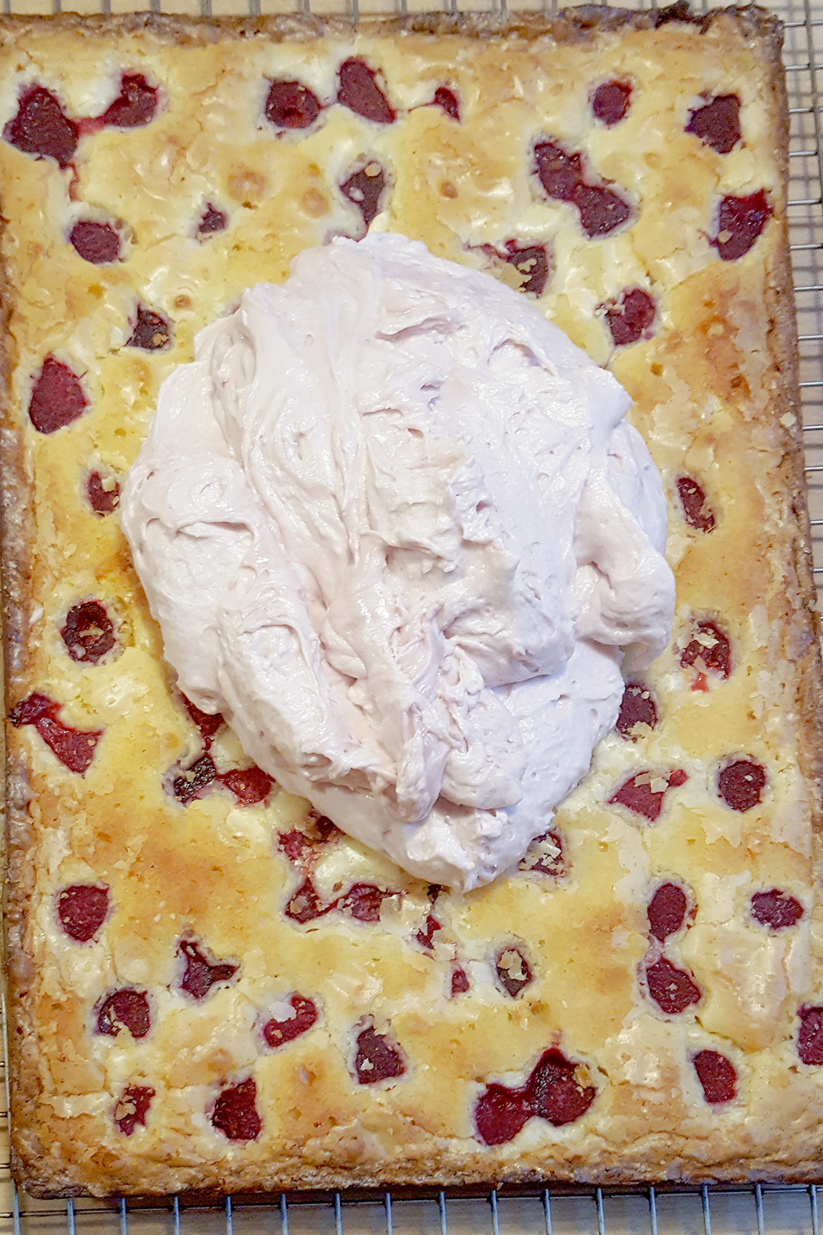 a baked sheet of white chocolate brownie with pink icing.