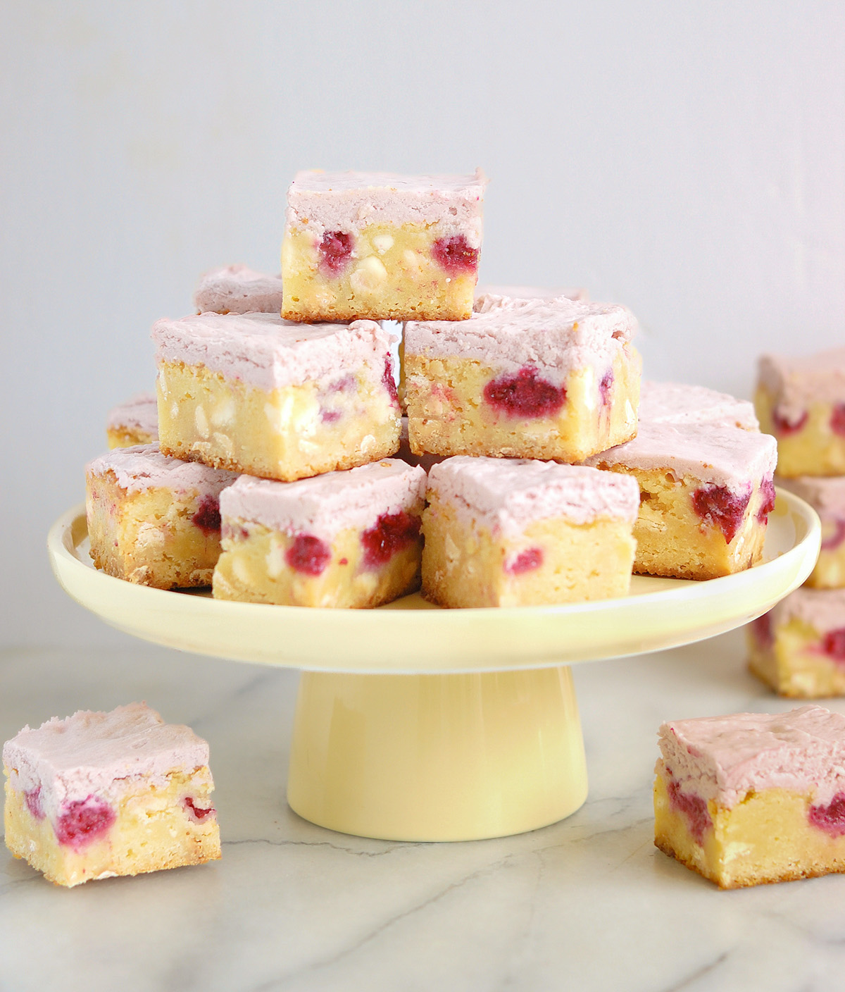 a yellow cake stand filled with white chocolate and raspberry brownies.