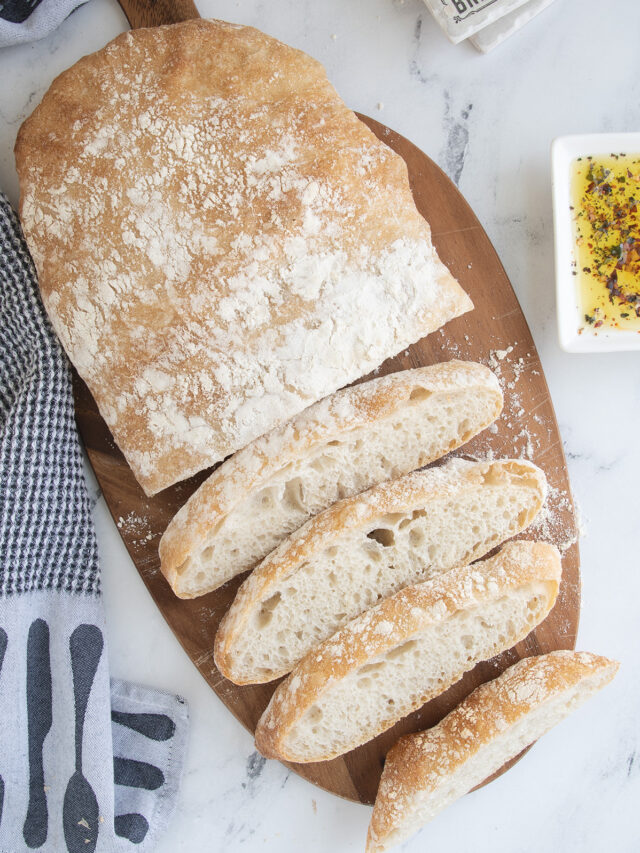 a sliced loaf of ciabatta bread on a cutting board.