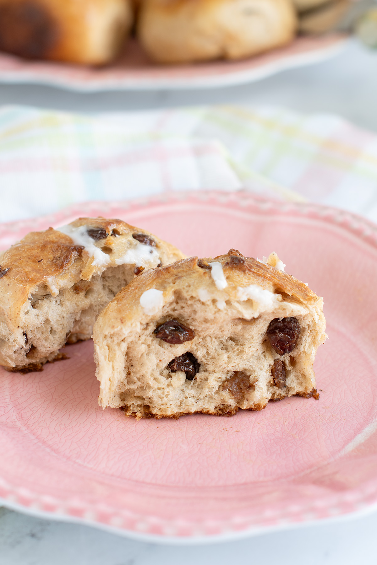 a split hot cross bun on a pink plate.