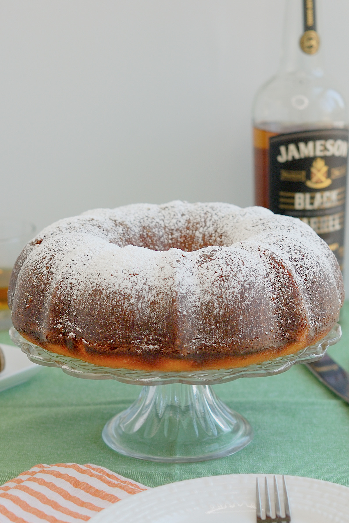 An irish whiskey cake on a glass cake stand.