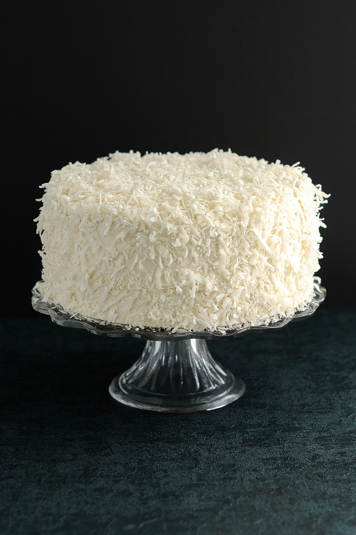 a coconut cake on a glass cake stand.