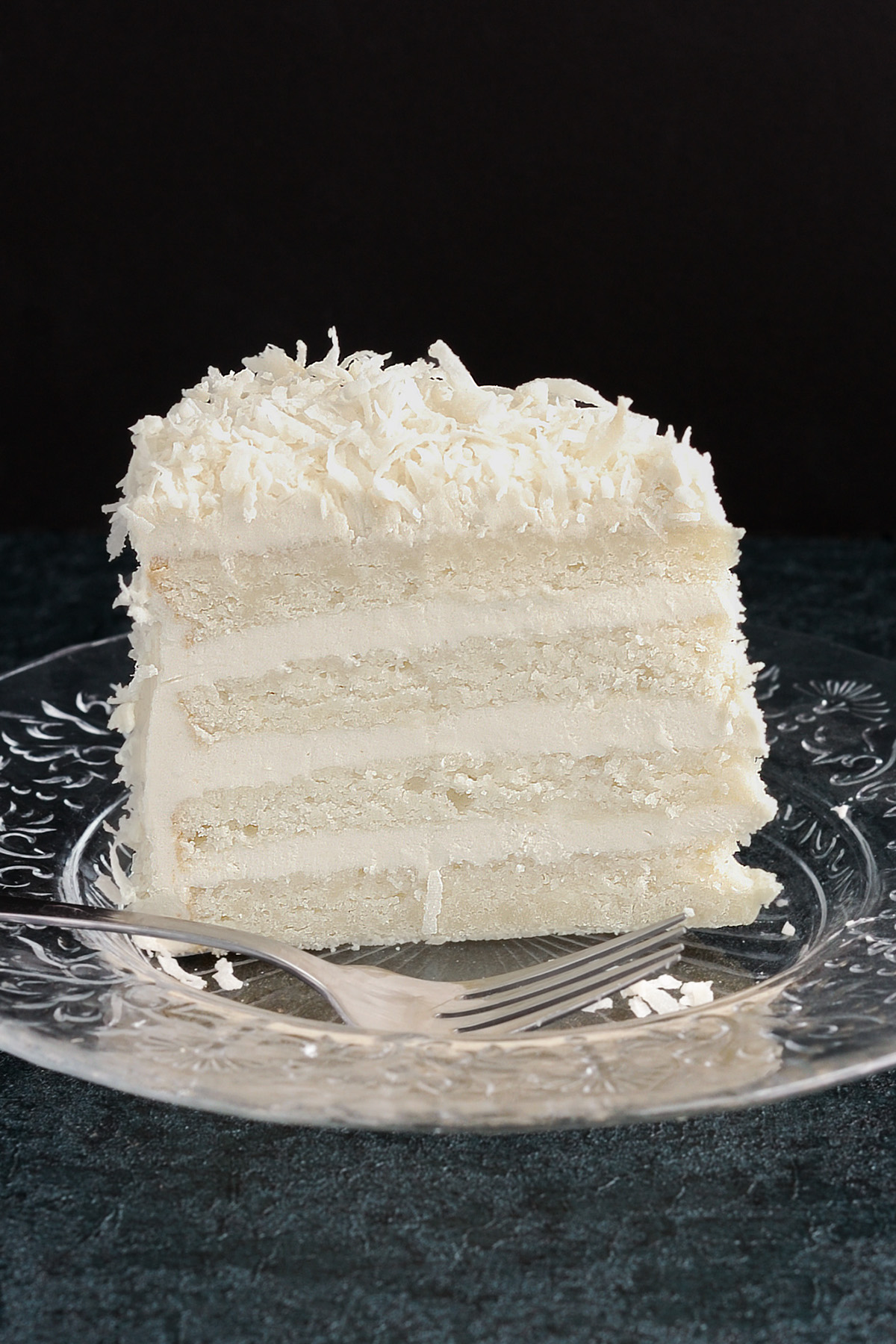 a slice of coconut cake on a glass plate.
