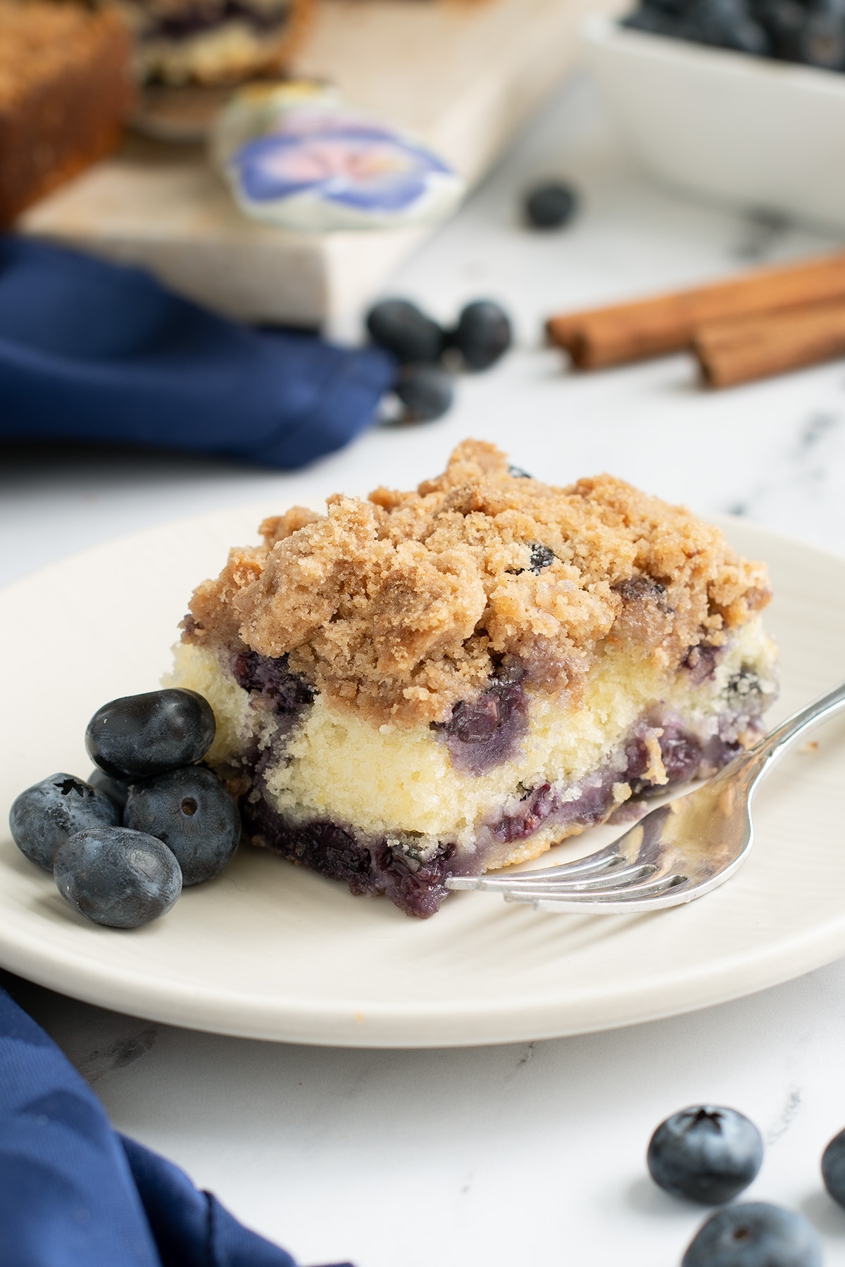 a slice of blueberry coffee cake on a white plate.