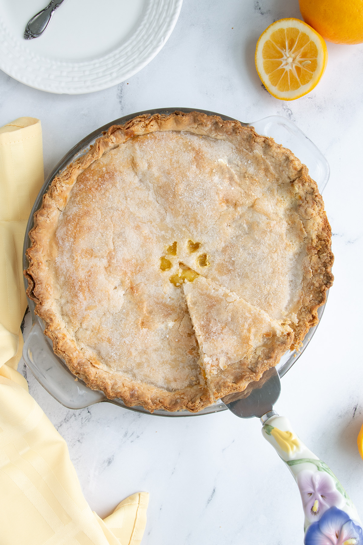 a lemon pie with a slice cut on a white surface.