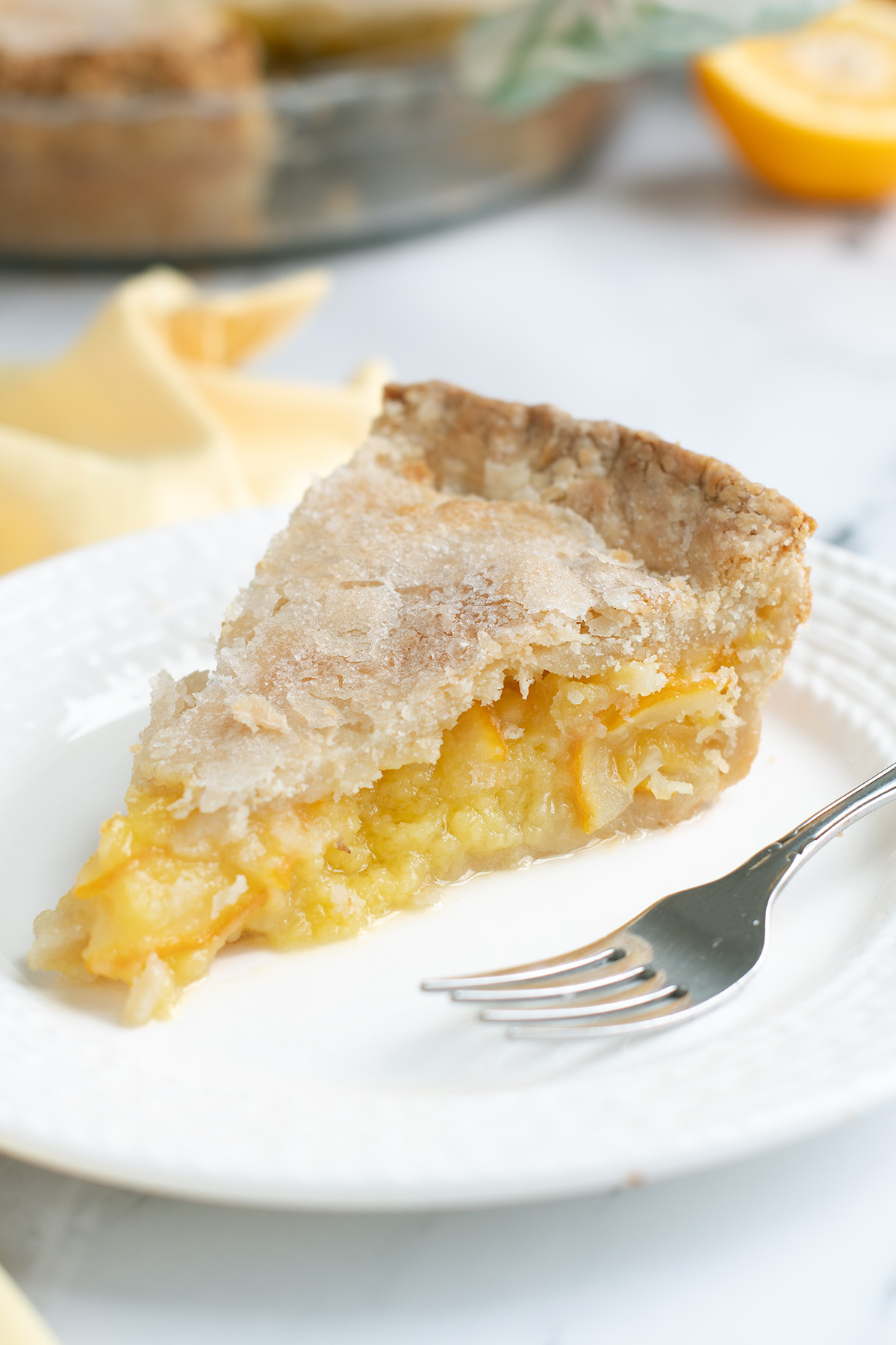 a slice of lemon pie on a white plate with a fork.