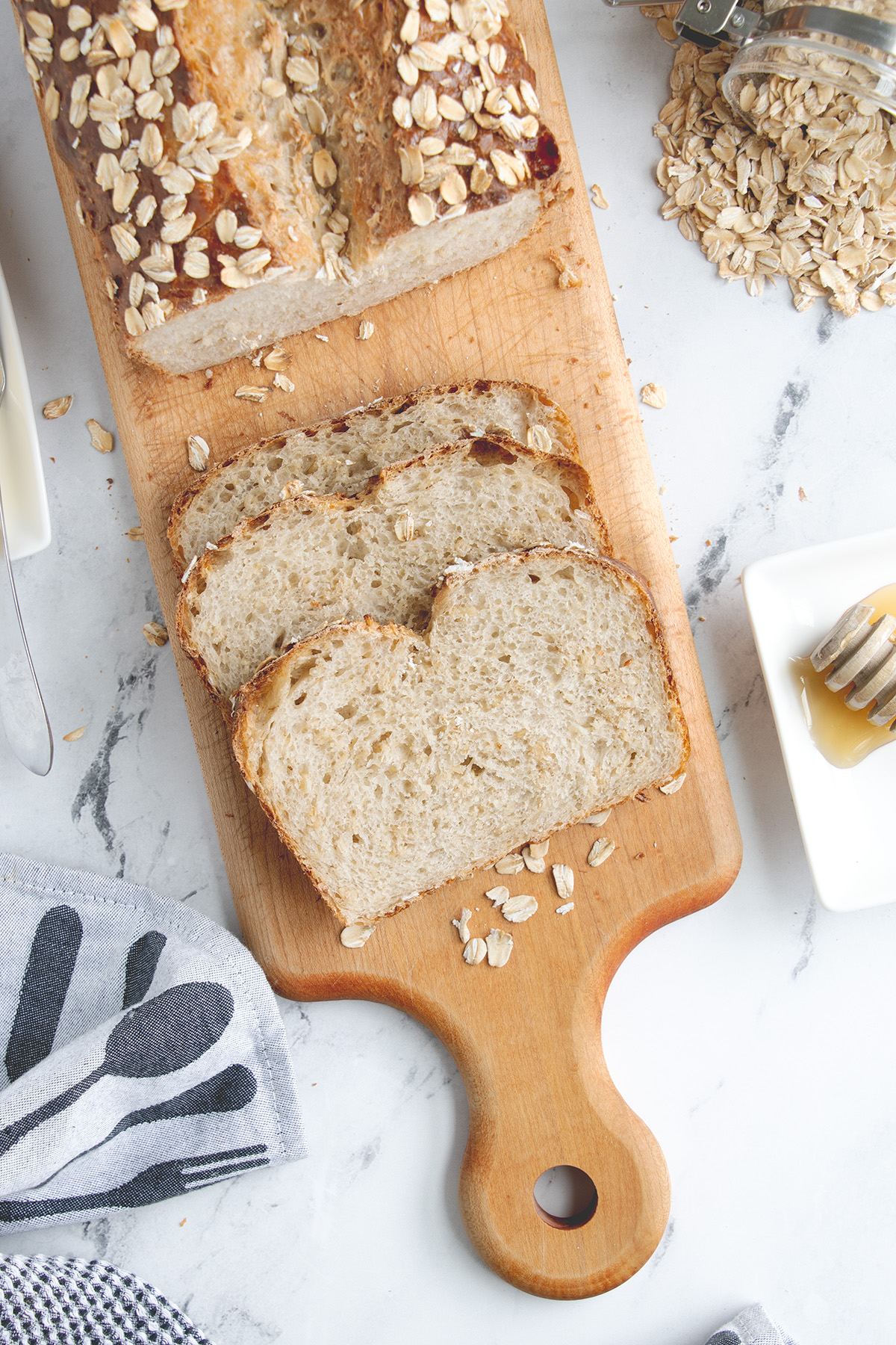 a sliced loaf of sourdough oatmeal bread on a cutting board.