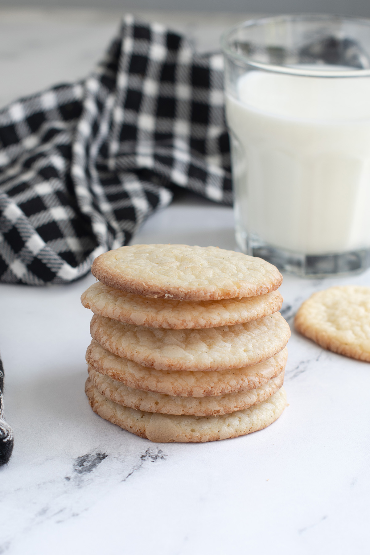 a stack of vanilla wafer cookies and a glass of milk.