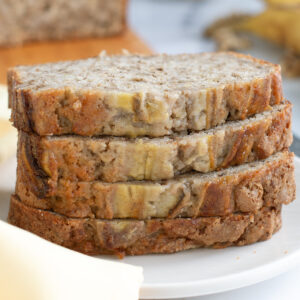 a stack of slices of banana nut bread on a white plate.