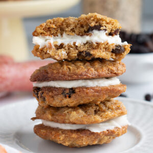 three carrot cake cookies stacked on a white plate.