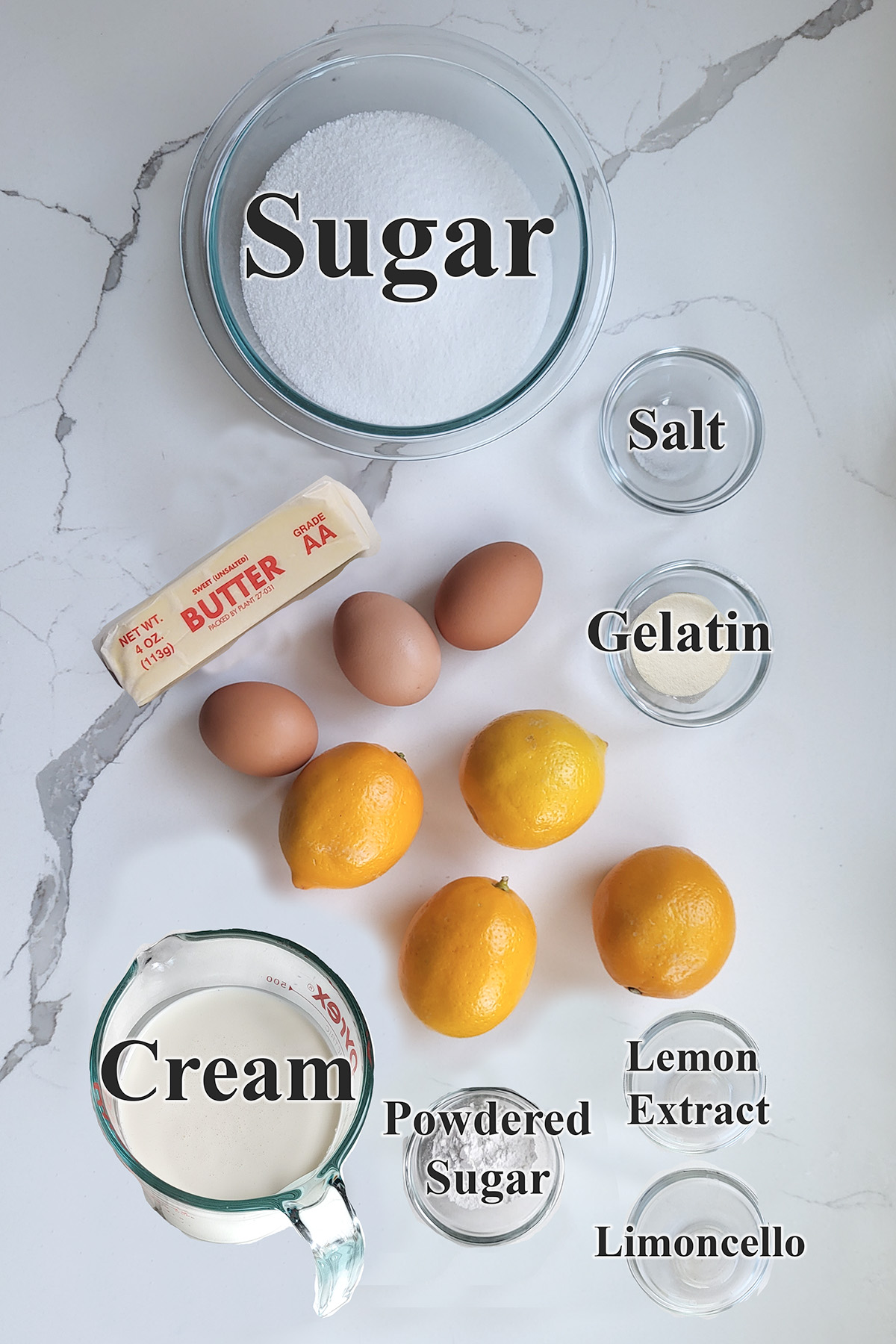 ingredients for lemon mousse in glass bowls on a white surface.