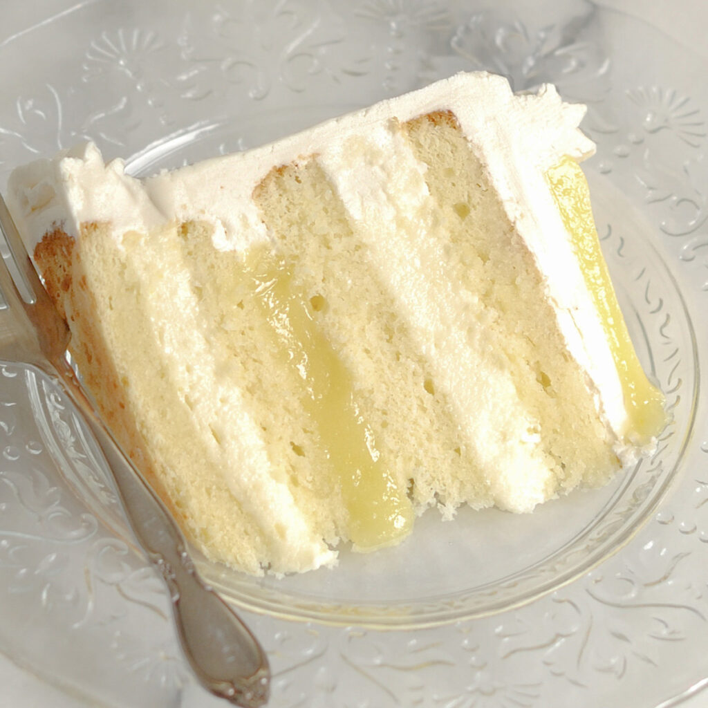 a slice of lemon mousse cake on a glass plate.