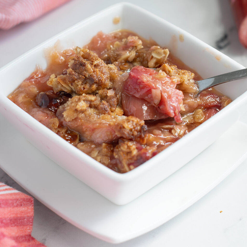 a white bowl filled with rhubarb crisp.
