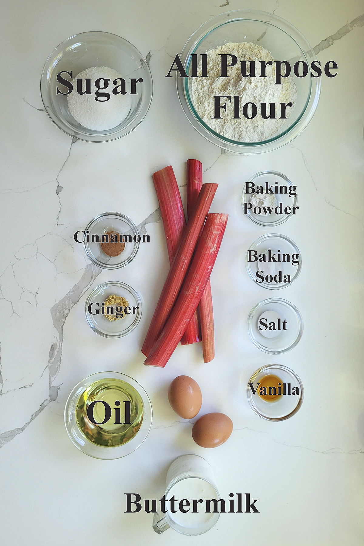 ingredients for rhubarb muffins in glass bowls on a white surface.