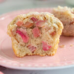 a split rhubarb muffin on a pink plate.